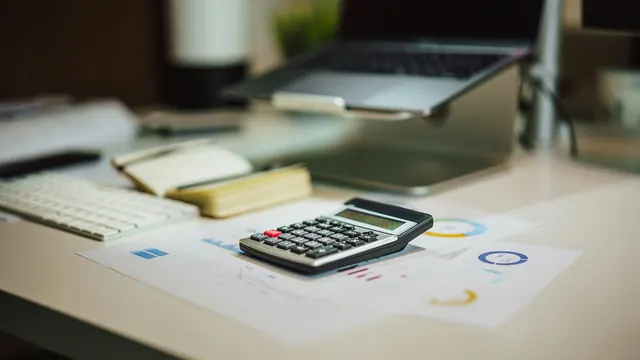 Calculator on a desk beside printed royalty charts