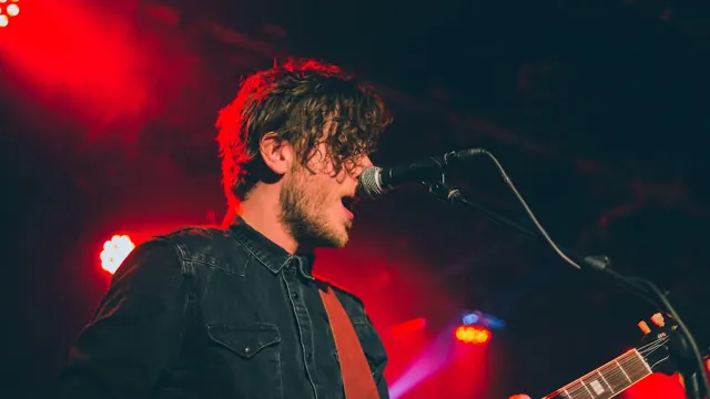 Independent artist performing on stage under red lights